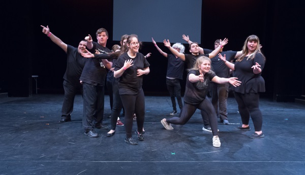 Young performers on stage pointing and arms raised